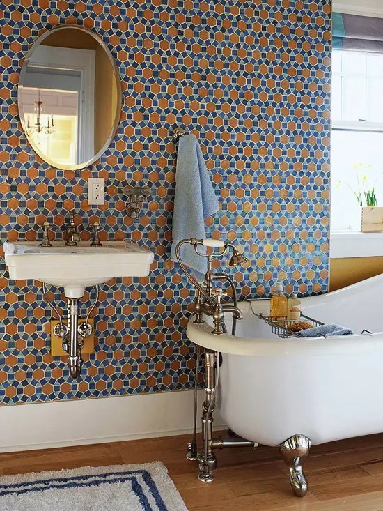 Parede estampada com azulejo mostarda, com uma banheira com pés e um espelho