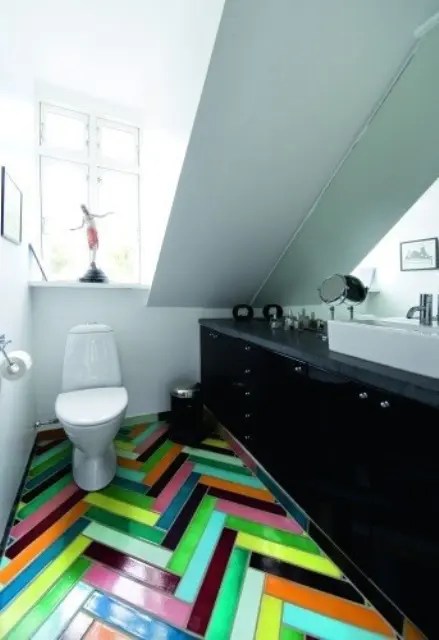 Banheiro com uma grande pia preta para armazenamento e um piso de ladrilho colorido em espinha de peixe