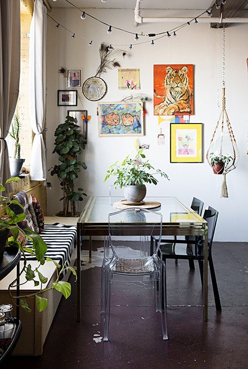 Sala com uma mesa de jantar, plantas, obras de arte e fio de luz no teto