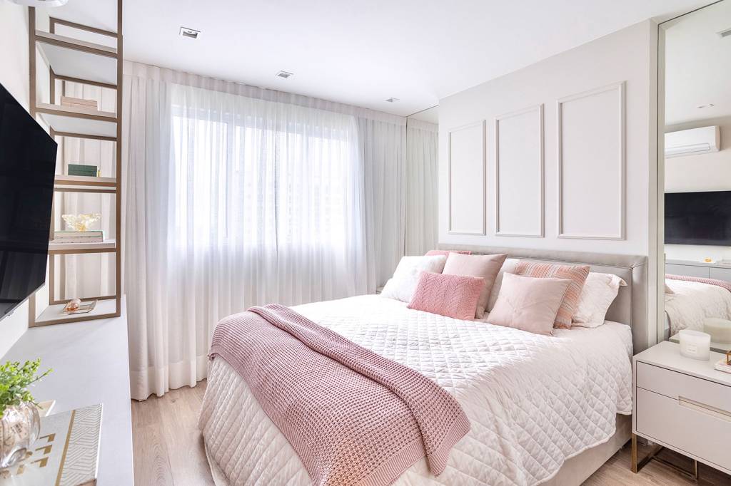 Quarto de casal, com cama com roupa de cama branca e manta rosa, nas paredes, boiseres