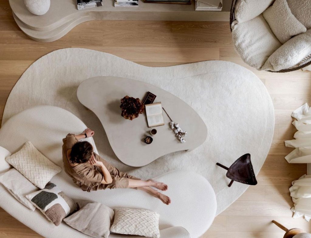 vista de cima de sofá branco curvo, mesa de centro em formato irregular curvo e tapete branco em formato orgânico