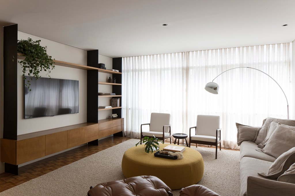 Sala de estar com décor neutro e minimalista, tapete, cortina e móveis assinados