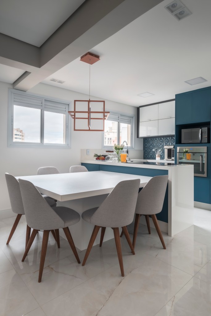 Cozinha com marcenaria azul e cadeiras brancas