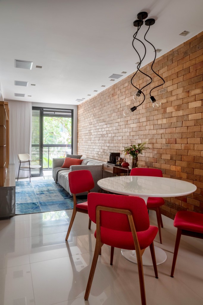 Sala de estar com parede de tijolinhos e cadeiras vermelhas