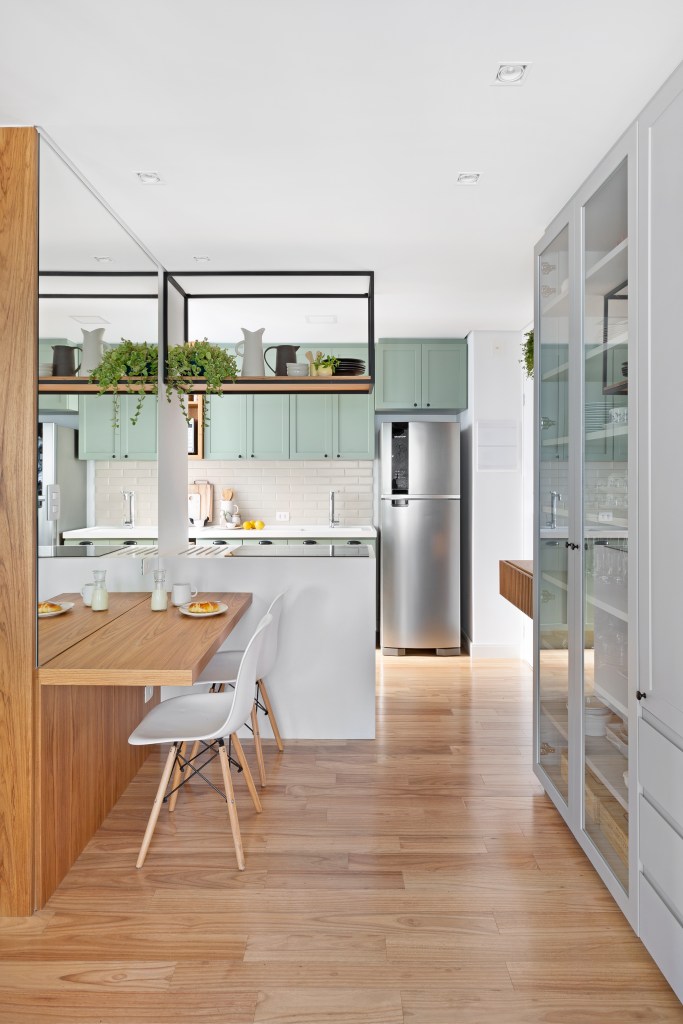 Cozinha de conceito aberto com bancada branca e armários em verde menta
