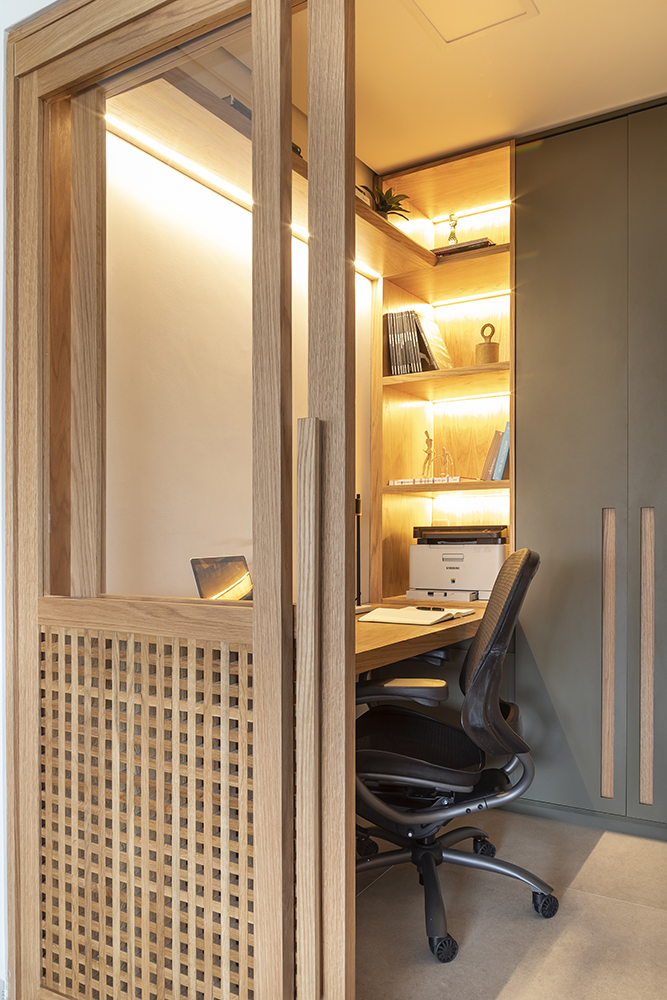 Home office compacto com mesa pequena e estante iluminada