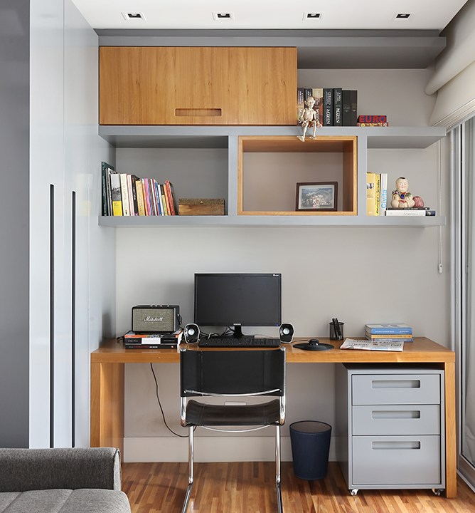 Home office com mesa em madeira e prateleira com nichos acima