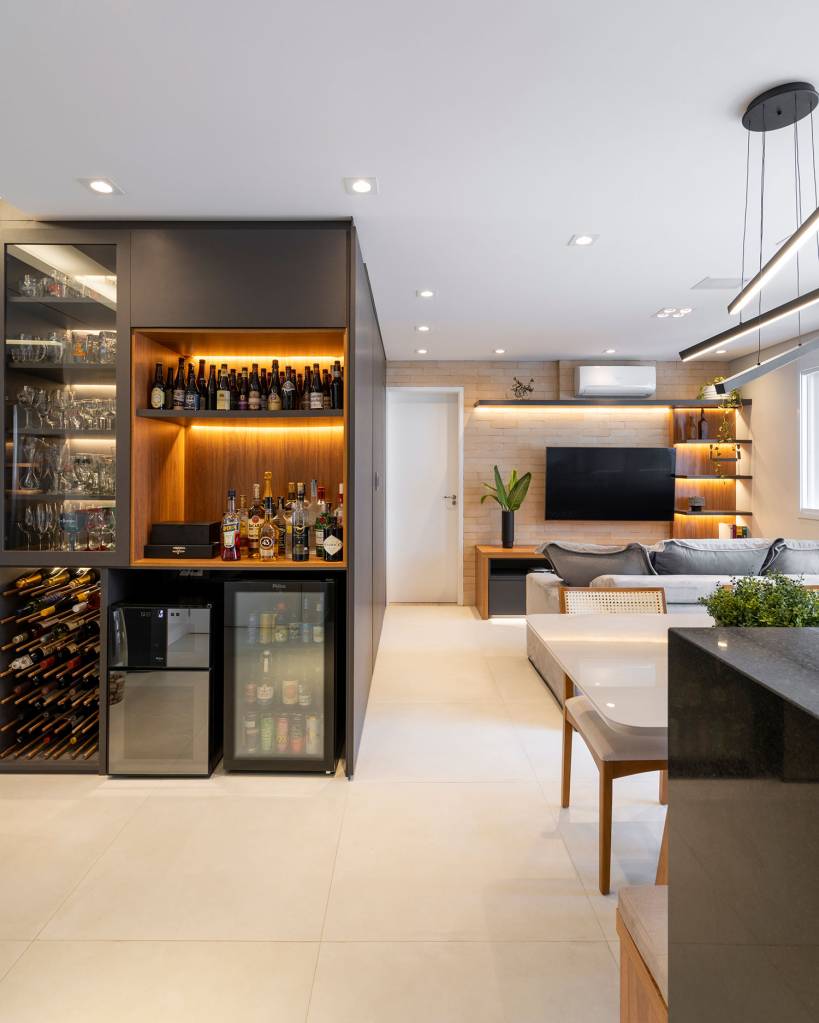 ape-de-55-m²-foi-feito-como-primeiro-imovel-de-um-jovem-casa.com-base-arquitetura-flavio-foto-estudio-360-16 Apartamento com sala integrada ampla mobiliário em preto, madeira e branco. Com um bar cheio de garrafas e adega