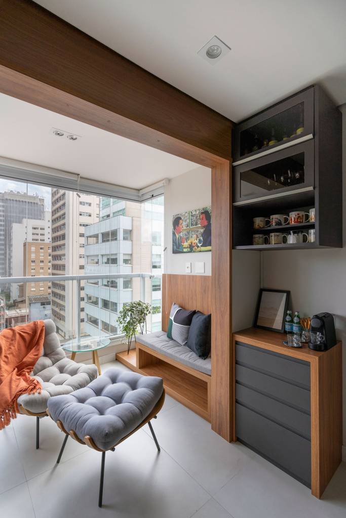 ape-de-55-m²-foi-feito-como-primeiro-imovel-de-um-jovem-casa.com-base-arquitetura-flavio-foto-estudio-360-26 Cantinho de leitura com poltrona e banco na varanda em apartamento com sala integrada