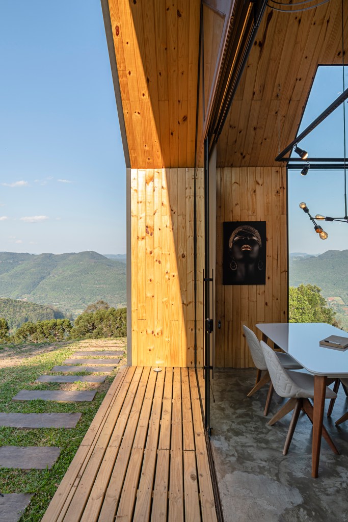 Detalhe da entrada de cabana contemporânea construída em steel frame com acabamento em madeira e vista da paisagem montanhosa.