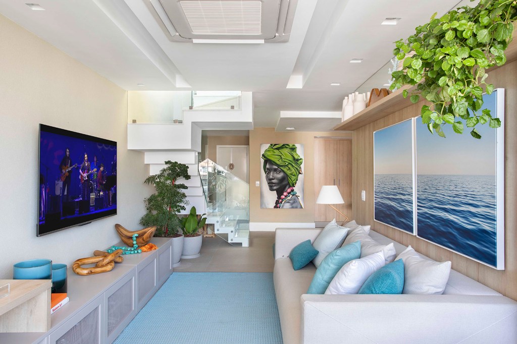 Sala de estar de cobertura dúplex, com móveis em cores claras e detalhes em azul claro