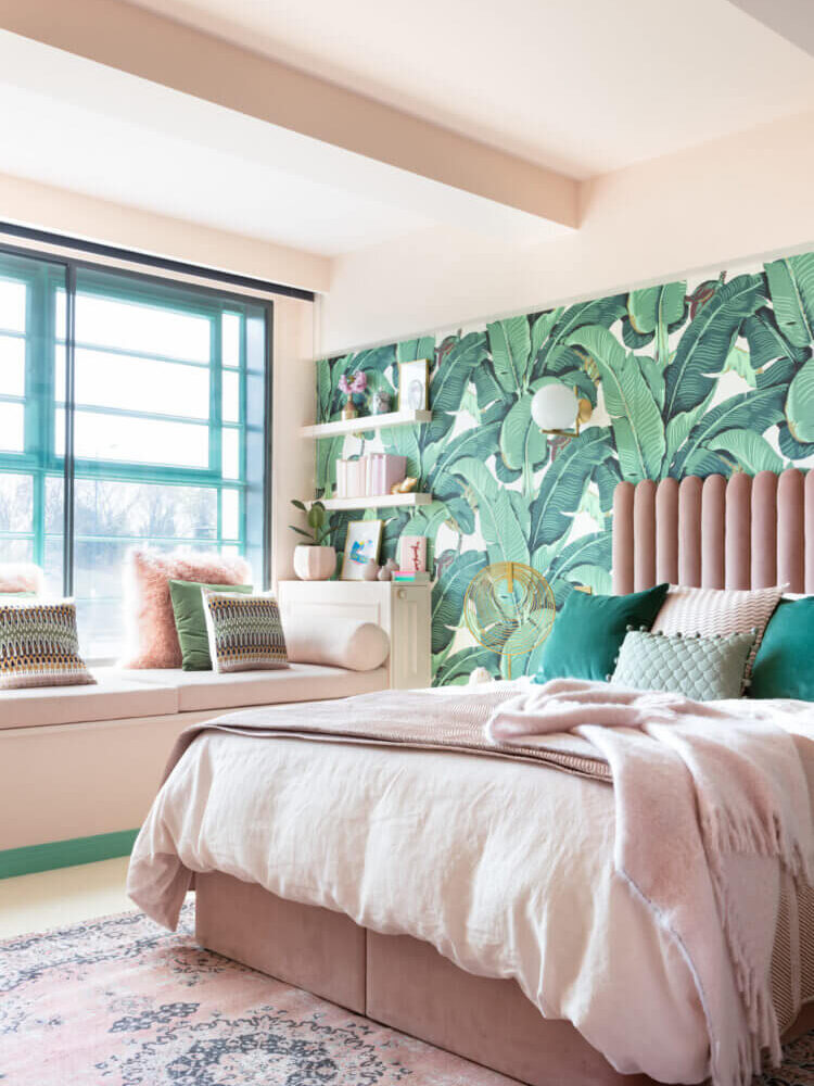 Quarto com cama rosa e papel de parede com folhas de bananeira