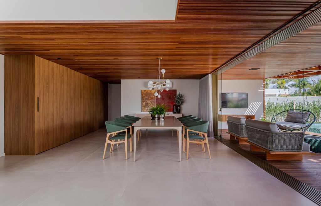 estilo-contemporaneo-guia-construcao-da-casa-muxarabi-na-bahia-casa.com-sidney-quintela-gabriela-daltro-17 Sala de jantar, com parede e teto de amdeira, e piso de cimento queimado. A mesa de oito lugares é cinza e tem as cadeira com estofado verde