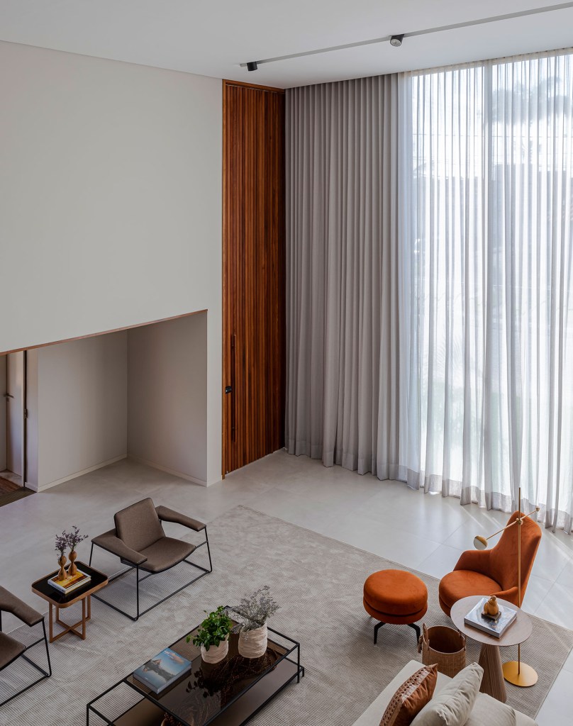 estilo-contemporaneo-guia-construcao-da-casa-muxarabi-na-bahia-casa.com-sidney-quintela-gabriela-daltro-25 Sala de estar vista de cima, com paredes em cimento queimado, e mobiliário emc reme, poltrona laranja e duas poltronas de couro