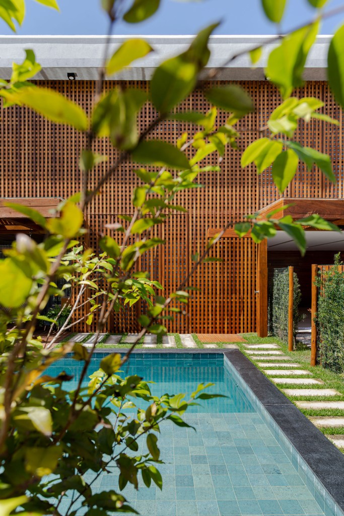 Piscina e fachada da casa, com muxarabi para fazer controle térmico da casa