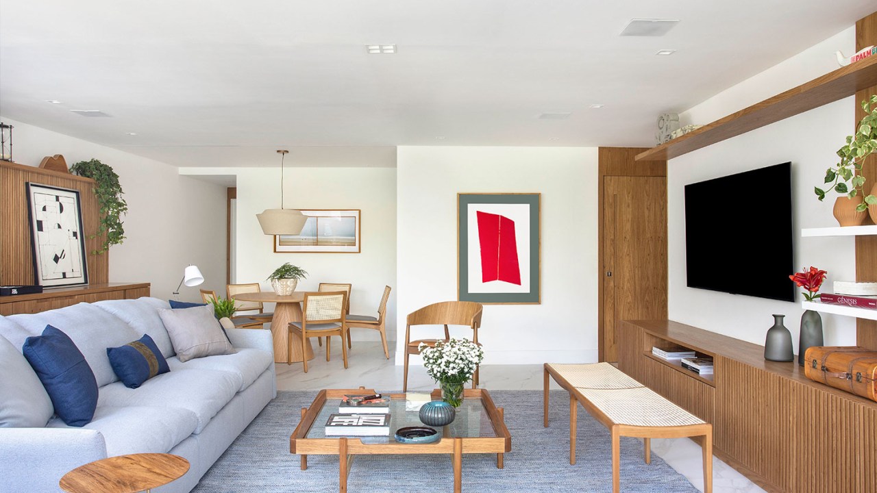 Sala de estar integrada com jantar, com painel de madeira e detalhes no mesmo material