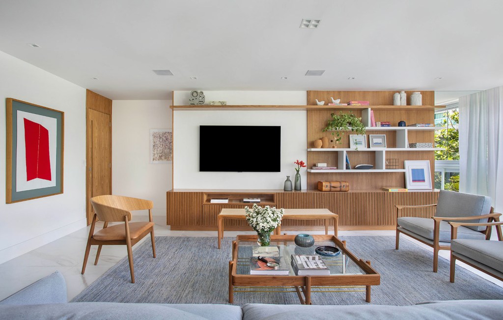 Sala de estar integrada com jantar, com painel de madeira e detalhes no mesmo material