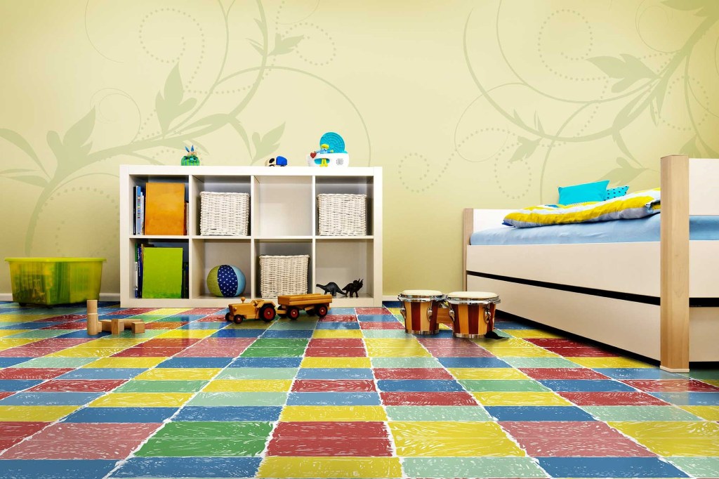 Quarto infantil com piso vinílico em quadrados coloridos, cama e estante baixa, brinquedos e objetos decorativos.