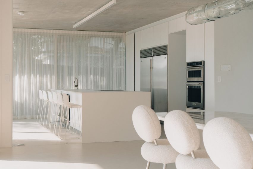 Cozinha minimalista toda branca, vista da sala de jantar