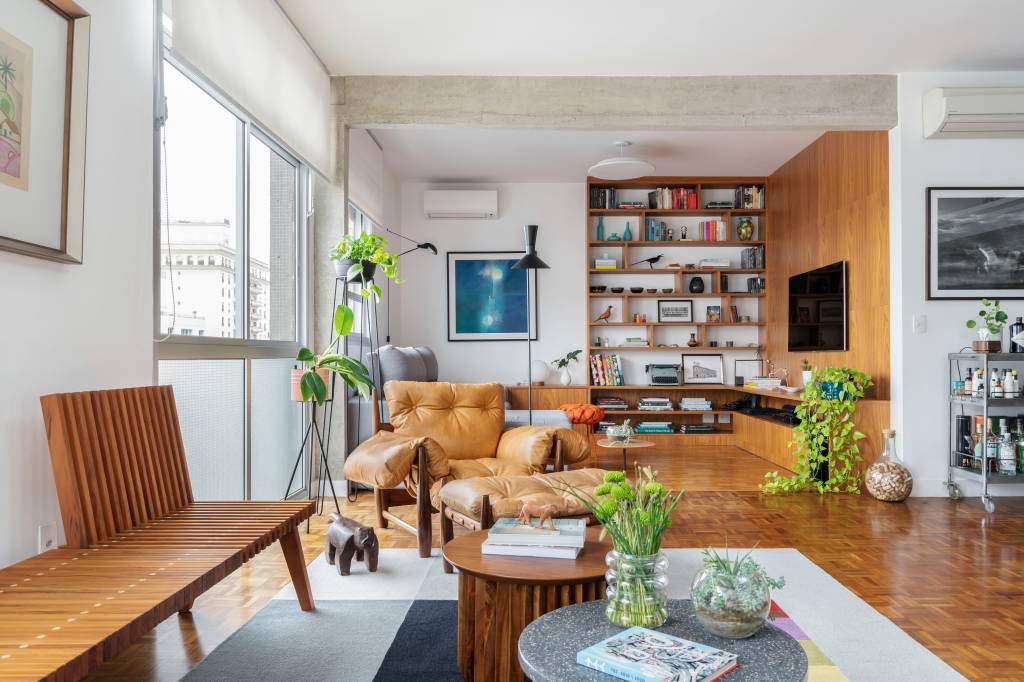 1-apê-de-140-m-2-ganha-cores-madeira-integração-e-décor-afetivo-com-reforma Sala de estar com muita madeira, livros e cores