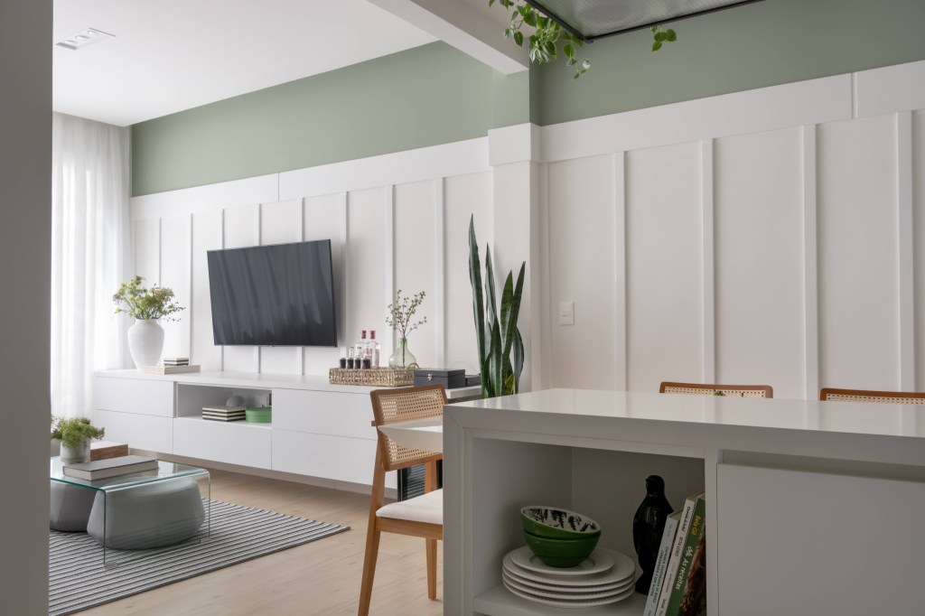 Sala de estar integrada ao jantar e à cozinha com parede com detalhe verde