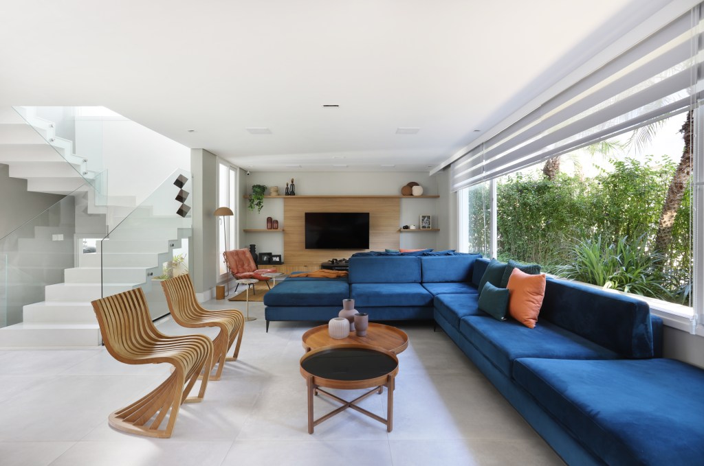 Sala ampla com luz natural, sofá azul e detalhes em madeira