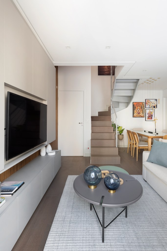 Sala de estar integrada com décor neutro e escada