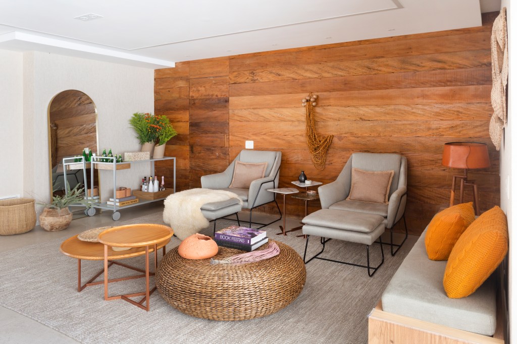 Sala de estar com painel de madeira e poltronas cinza