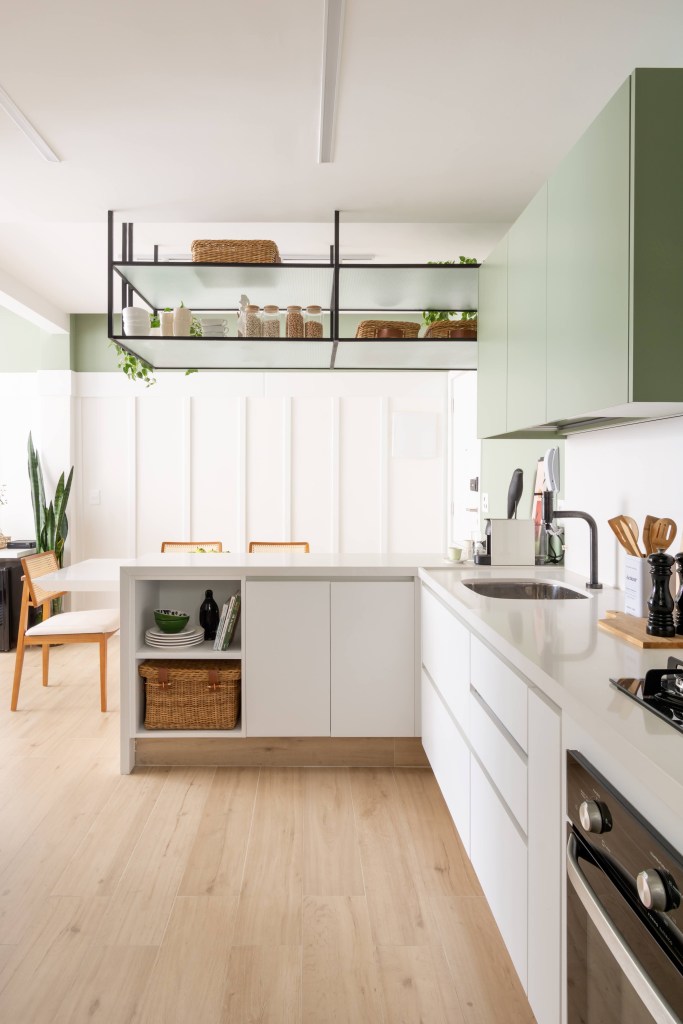 Cozinha com detalhes verdes integrada à sala de estar
