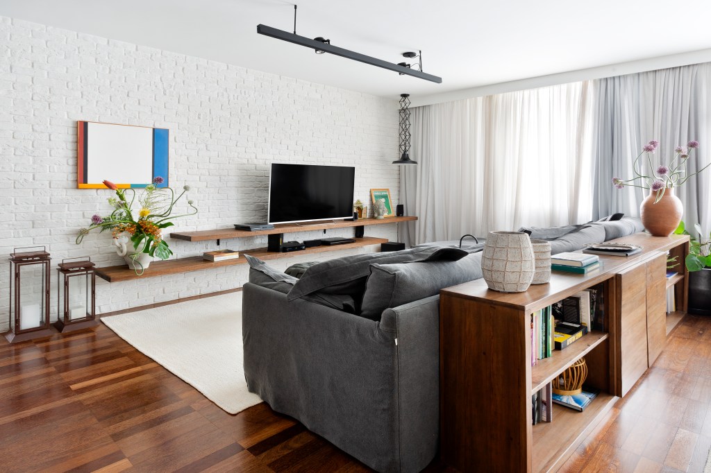 Sala de estar integrada com base neutra e piso de madeira