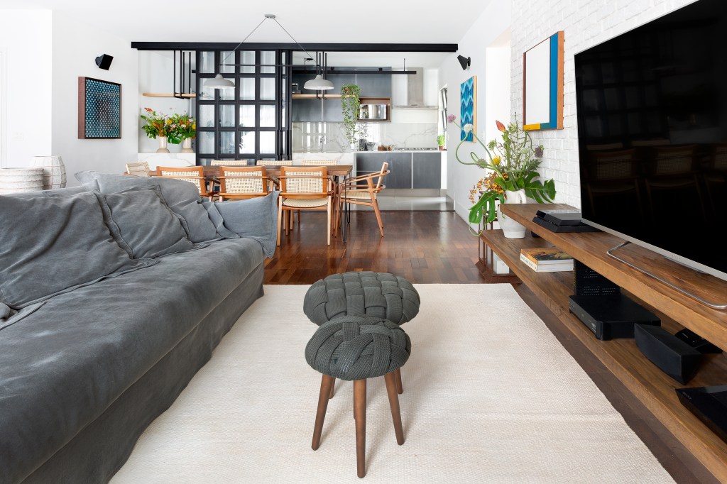 Sala integrada com piso de madeira e sofá cinza
