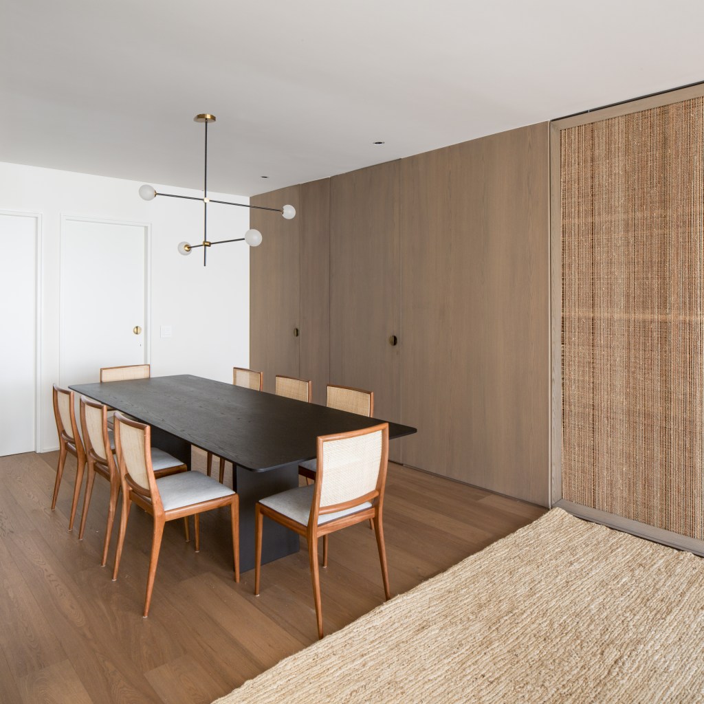 Sala de jantar com mesa e cadeiras de design e painel de madeira