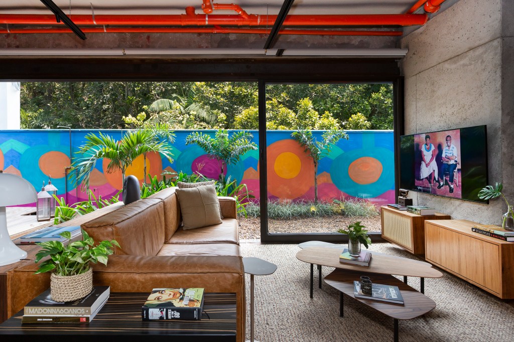 sala integrada à área externa com muro pintado e colorido e portas de correr de vidro