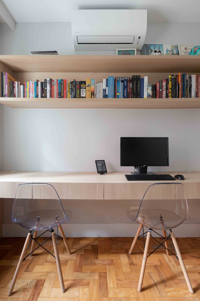 Home office com prateleira e mesa de madeira e cadeiras transparentes