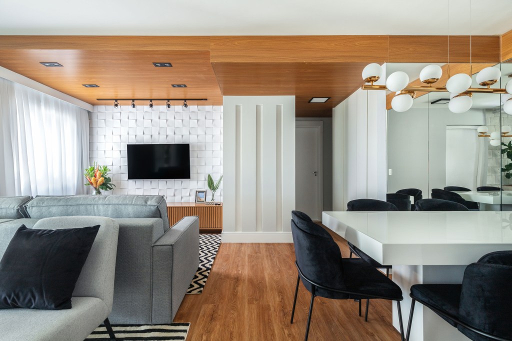 Sala de estar e jantar integradas com piso de madeira e detalhes em madeira, tons neutros