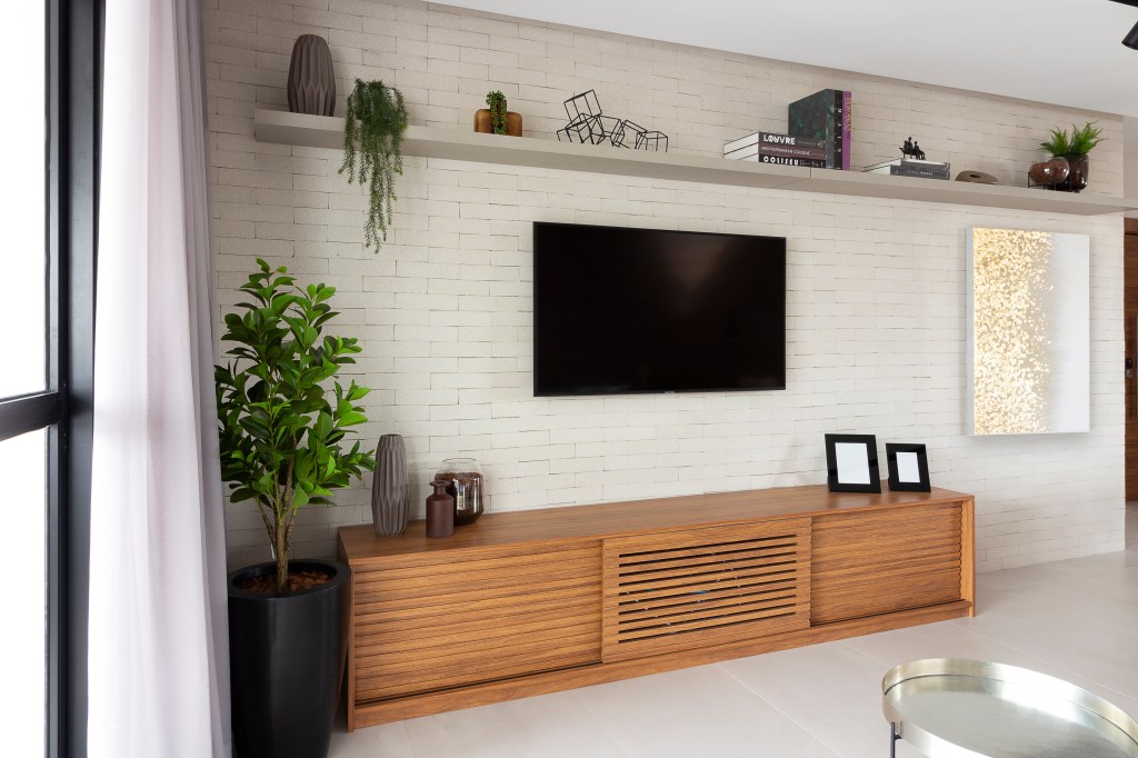 Sala de estar com TV suspensa na parede e móvel de madeira