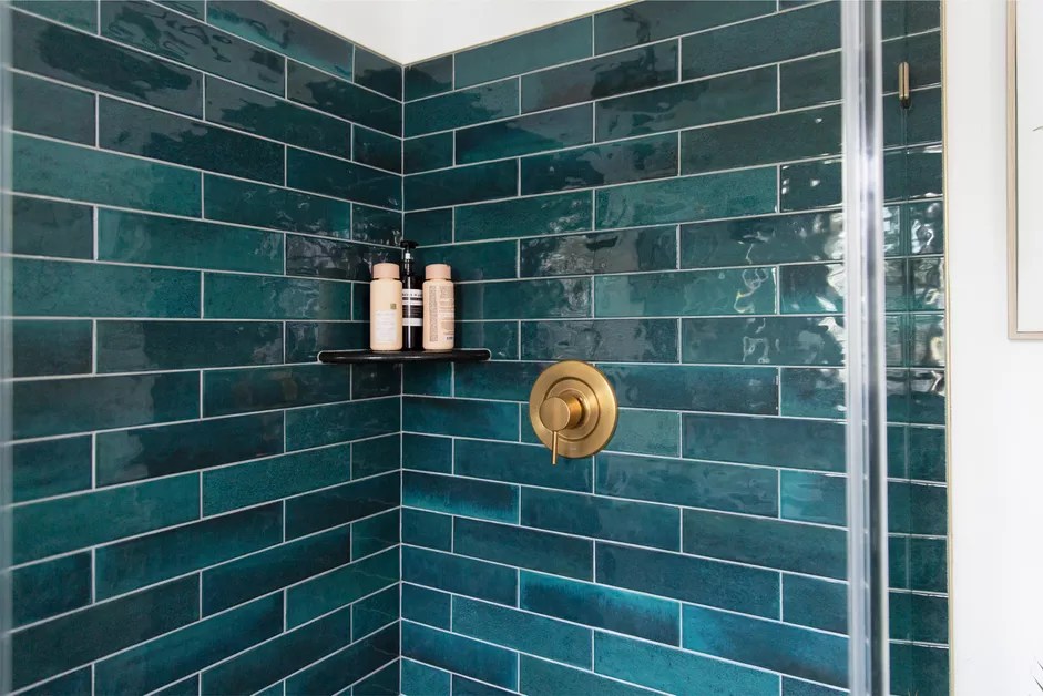 Paredes de box de banheiro revestidas com azulejos retangulares azuis.