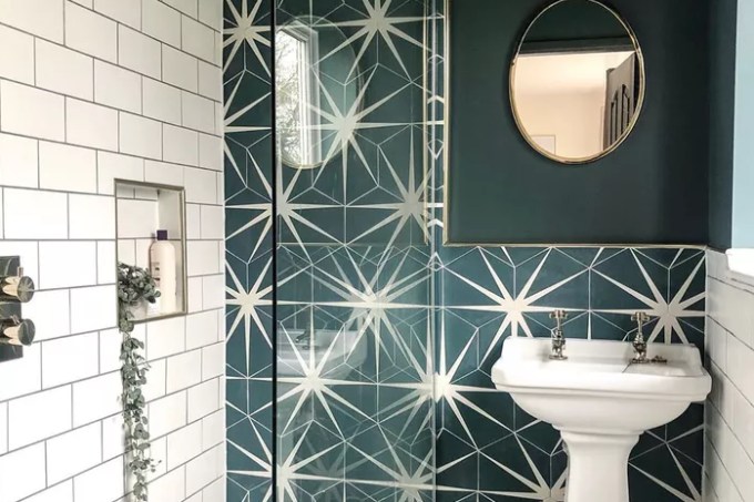 Banheiro com revestimento em ladrilhos brancos com exceção de uma das paredes, que é coberta em ladrilhos com estampa estrelada, em branco e verde escuro.