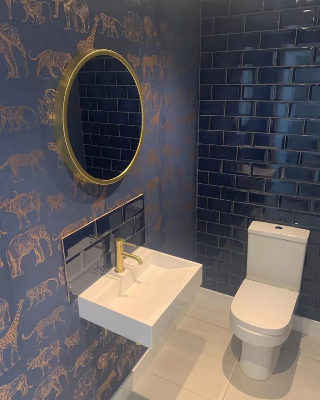 O azul marinho é uma ótima cor para criar um espaço elegante e tradicional. Este banheiro da doingupduke apresenta um azul marinho profundo com linhas de rejunte escuras, muita elegância. Ainda é combinado com um papel de parede de estampa animal que dialoga maravilhosamente com os azulejos.
