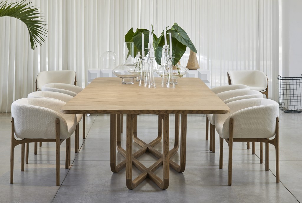 Mesa de jantar de madeira, com quatro cadeiras brancas com pés de madeira.
