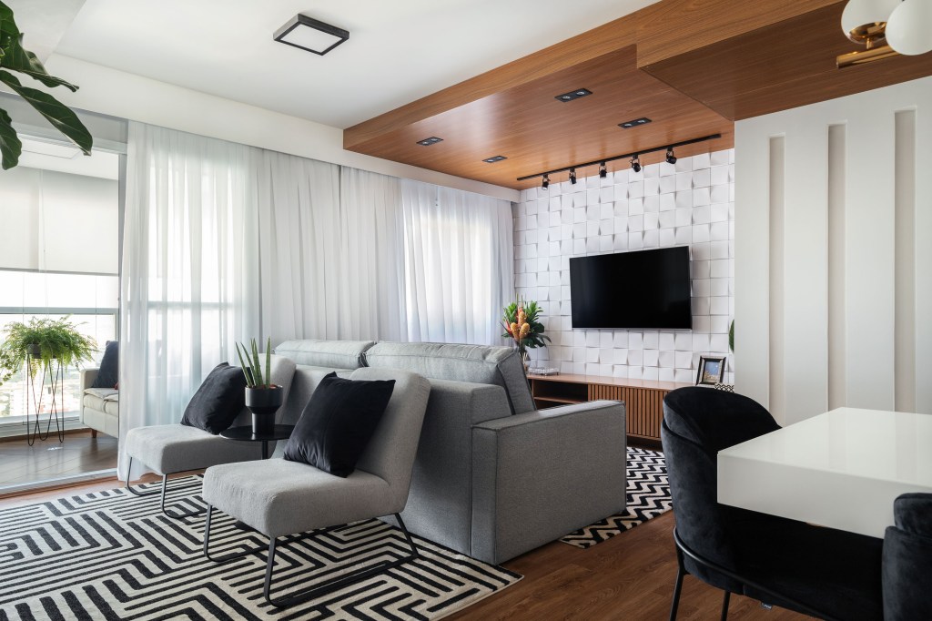 Sala de estar com décor neutro, tapete branco e preto e sofá cinza
