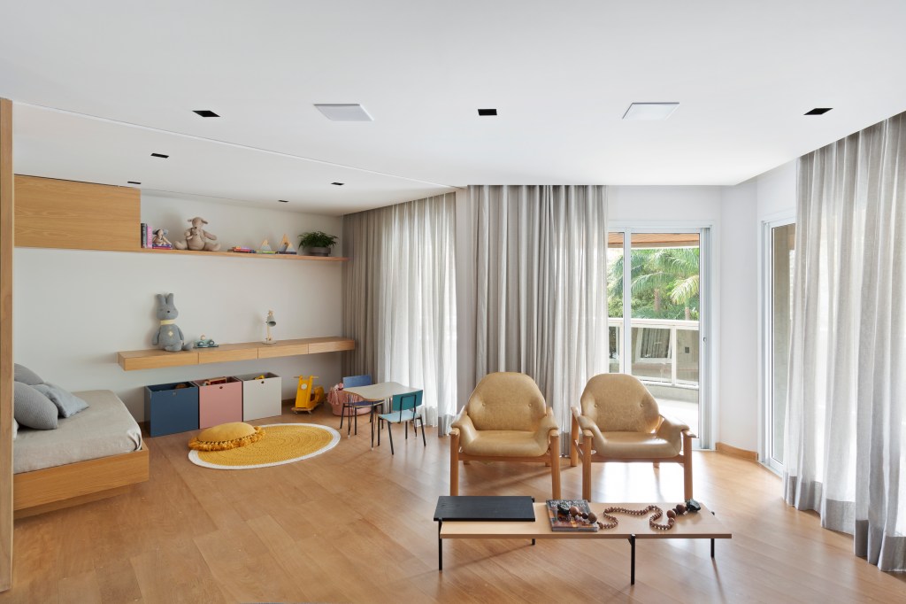 Sala de estar integrada à brinquedoteca com base neutra de madeira e detalhes cinza