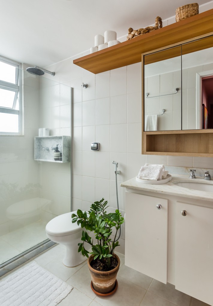 Banheiro branco com sanitário; box de banho; pia e bancada