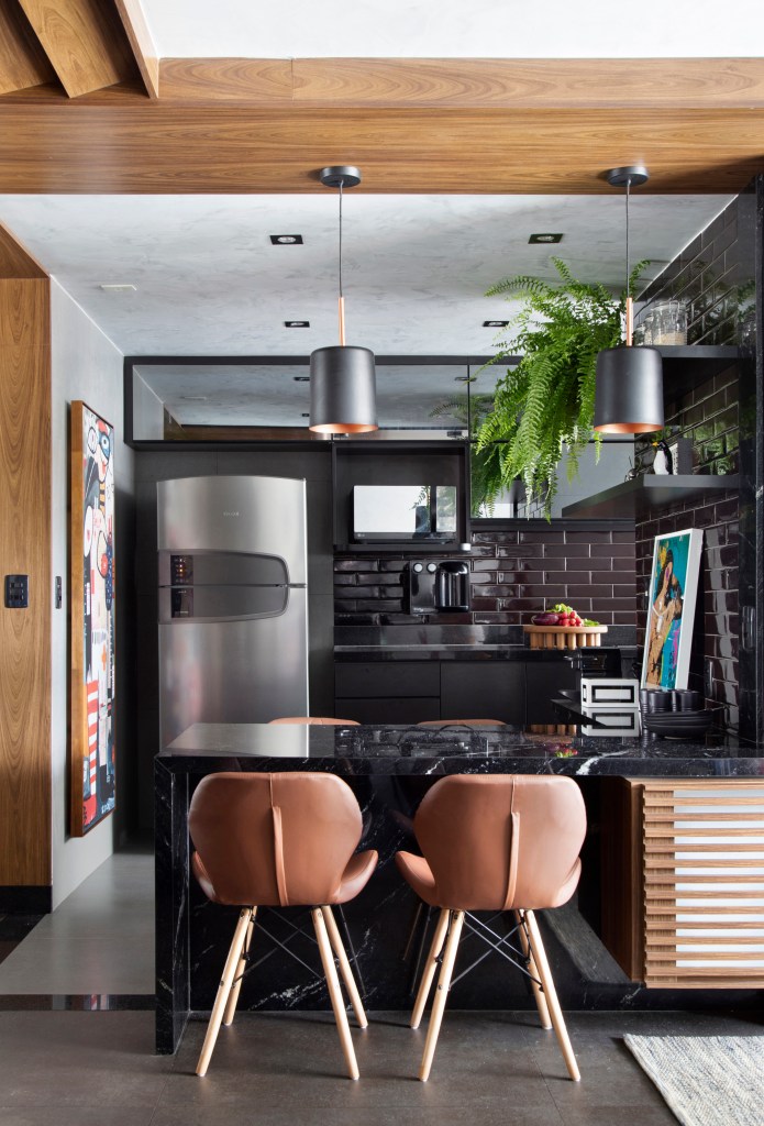 Cozinha integrada com estar; mesa preta; cadeiras em couro marrom