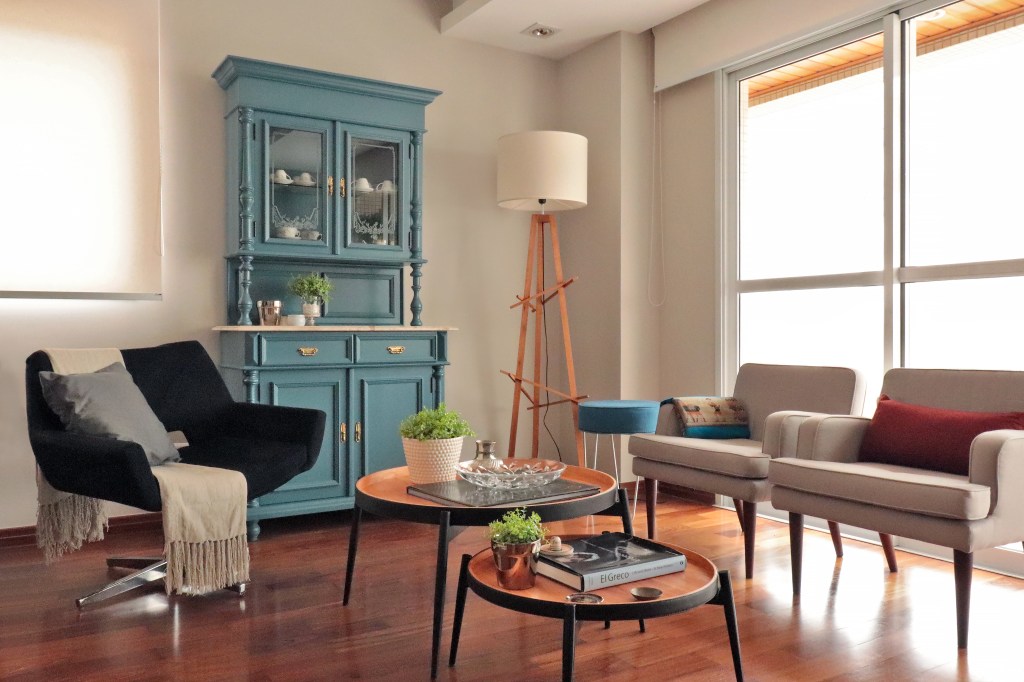 Sala de estar moderna que conta com uma cristaleira em estilo mais antigo, entalhada em madeira e pintada com um tom de azul turquesa.
