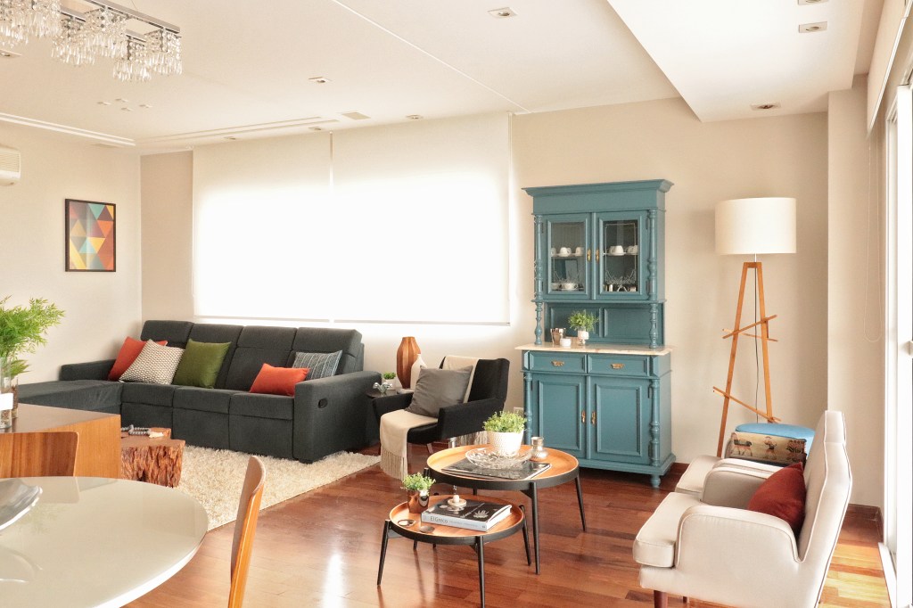 Sala de estar moderna que conta com uma cristaleira em estilo mais antigo, entalhada em madeira e pintada com um tom de azul turquesa.