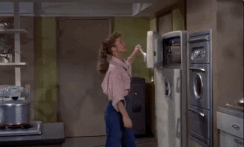 Gif de uma mulher abrindo o congelador de uma geladeira dúplex para se refrescar.