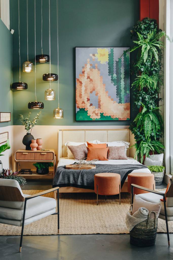 Quarto mobiliado com móveis em tons complementares de bege e cinza. A parede de cabeceira se destaca pela cor verde pastel e o quadro, releitura de Abaporu.