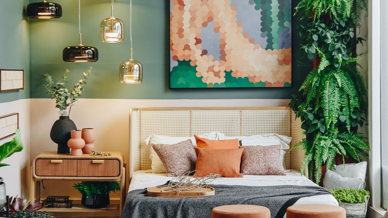 Quarto mobiliado com móveis em tons complementares de bege e cinza. A parede de cabeceira se destaca pela cor verde pastel e o quadro, releitura de Abaporu.