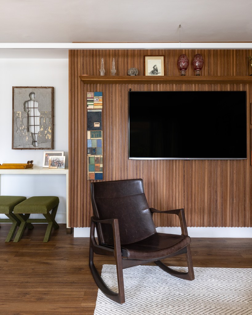 Sala de estar com poltrona; painel de tv em madeira